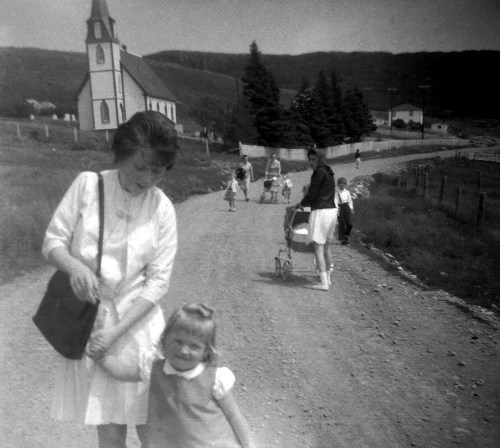 Women and children walking along a gravel road.