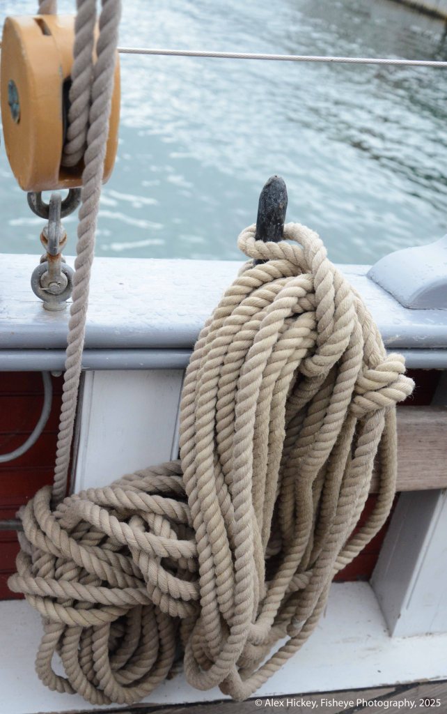 Coiled rope hanging on the bulwark of a sailing schooner.